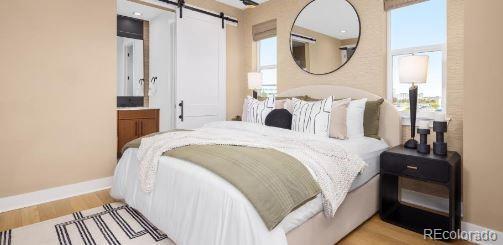 10886 E Hinsdale Cir, Centennial, CO 80112 - bedroom with a barn door, baseboards, and wood finished floors