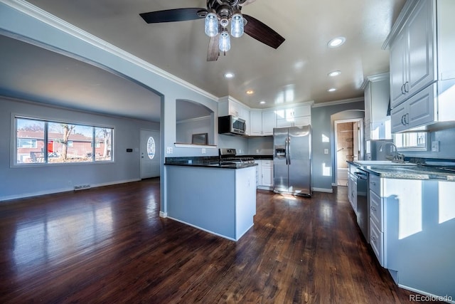 kitchen featuring stainless steel appliances, arched walkways, dark wood finished floors, and ornamental molding