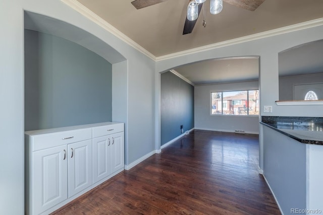 interior space with dark wood-style floors, baseboards, arched walkways, and crown molding