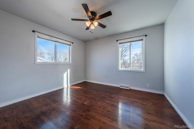 empty room with a wealth of natural light, visible vents, and wood finished floors