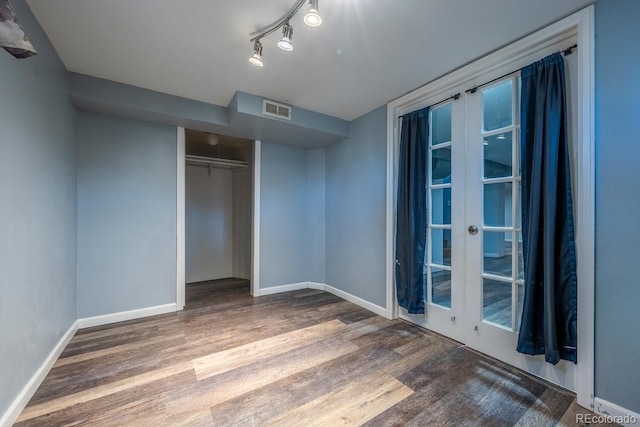 unfurnished bedroom featuring wood finished floors, visible vents, and baseboards