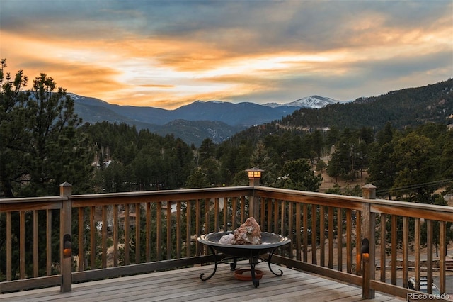 deck at dusk featuring a mountain view and an outdoor fire pit