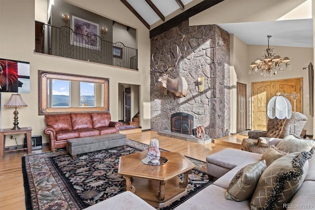 living room featuring high vaulted ceiling, a notable chandelier, wood-type flooring, a stone fireplace, and beamed ceiling
