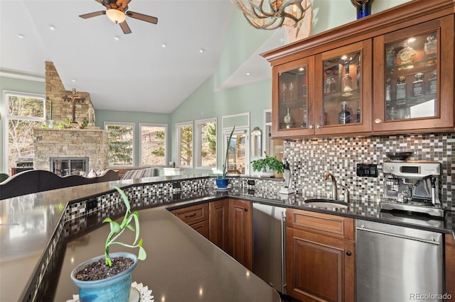 kitchen with a stone fireplace, dishwasher, lofted ceiling, sink, and decorative backsplash