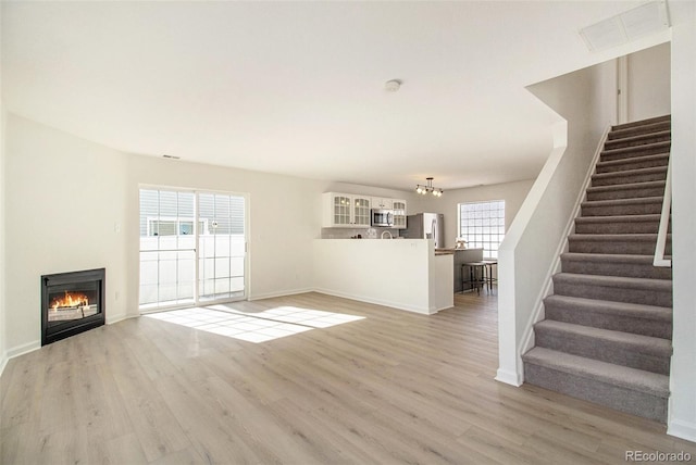 unfurnished living room featuring a chandelier and light hardwood / wood-style flooring