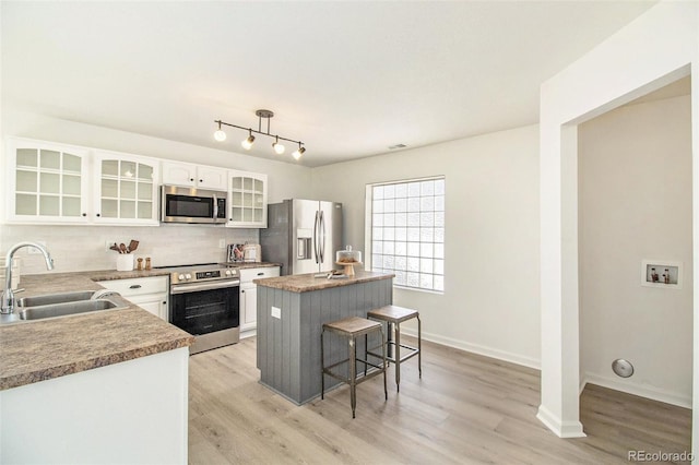 kitchen featuring sink, a center island, white cabinetry, stainless steel appliances, and a breakfast bar area