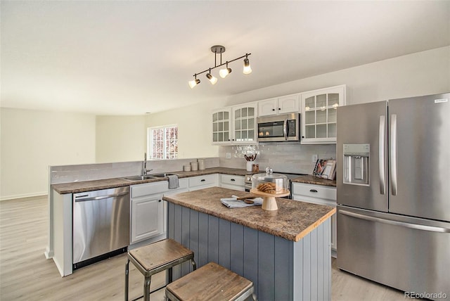 kitchen featuring appliances with stainless steel finishes, a kitchen breakfast bar, sink, light hardwood / wood-style floors, and a center island