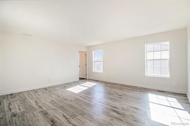 empty room with light hardwood / wood-style flooring and plenty of natural light