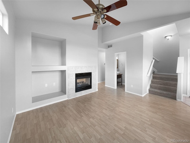 unfurnished living room featuring lofted ceiling, light hardwood / wood-style flooring, ceiling fan, built in features, and a fireplace