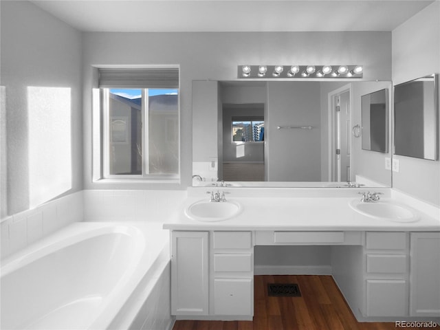 bathroom with tiled tub, vanity, and wood-type flooring