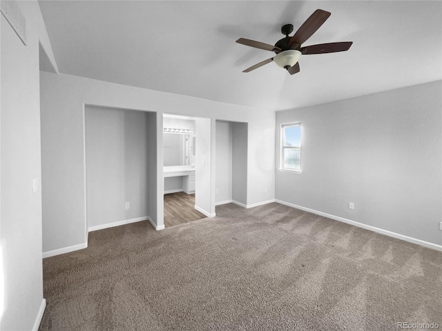 unfurnished bedroom featuring dark colored carpet, ensuite bathroom, and ceiling fan