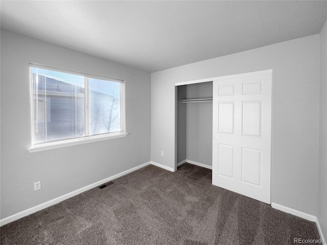 unfurnished bedroom featuring a closet and dark colored carpet