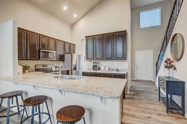 kitchen featuring light stone counters, a breakfast bar, a high ceiling, and appliances with stainless steel finishes