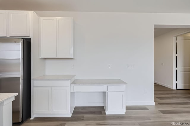 15153 W Dequesne Ave, Morrison, CO 80465 - kitchen with stainless steel fridge, light wood-style flooring, white cabinetry, baseboards, and light stone counters