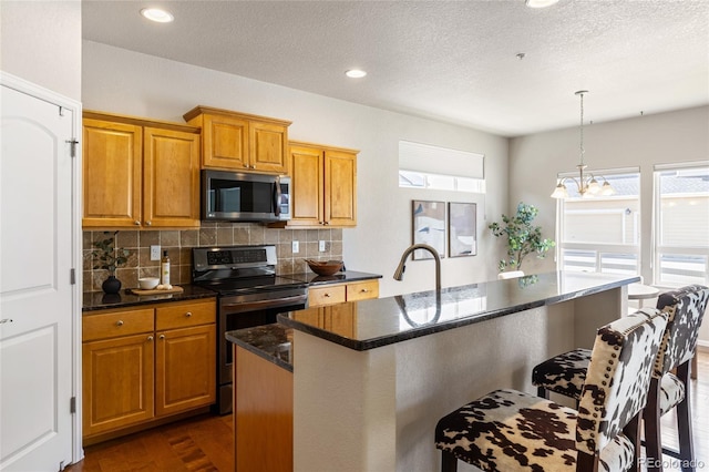 kitchen with decorative backsplash, brown cabinets, stainless steel appliances, and an inviting chandelier