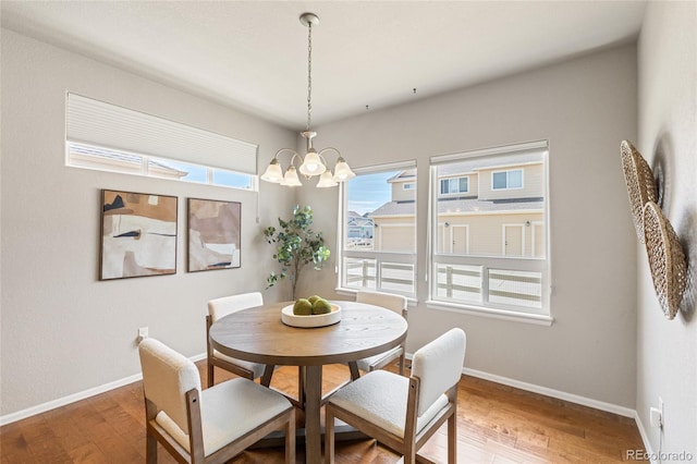 dining area with baseboards, a notable chandelier, and wood finished floors