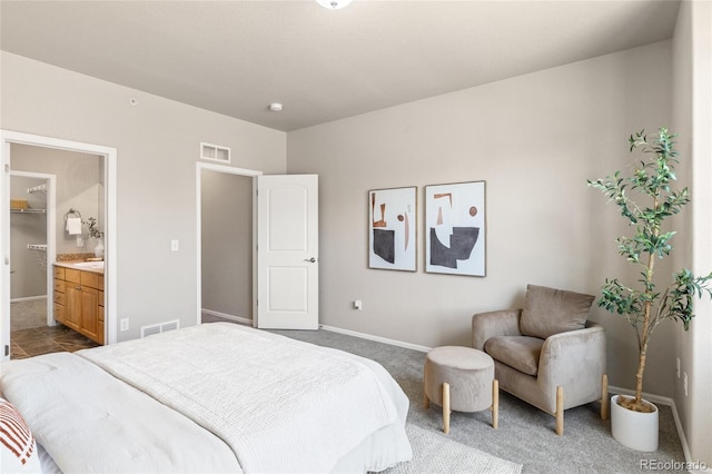 bedroom with baseboards, dark colored carpet, visible vents, and ensuite bathroom