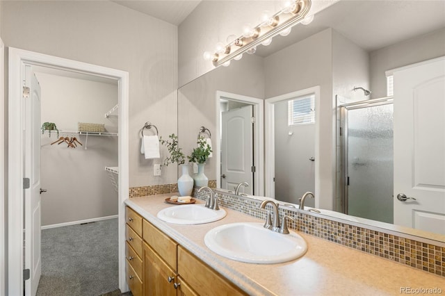 bathroom featuring a spacious closet, a sink, double vanity, and a stall shower