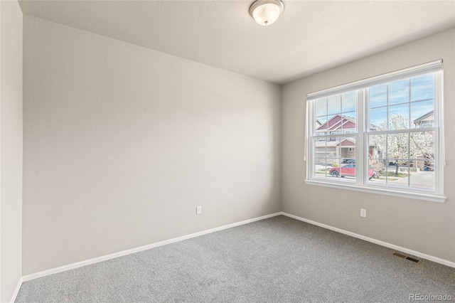 carpeted spare room with visible vents and baseboards