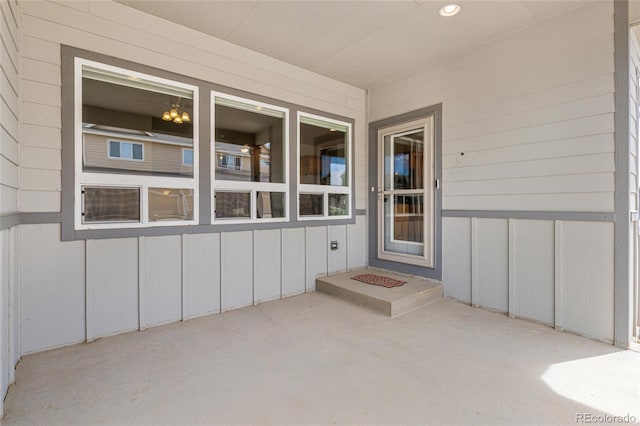 view of exterior entry featuring board and batten siding and a patio