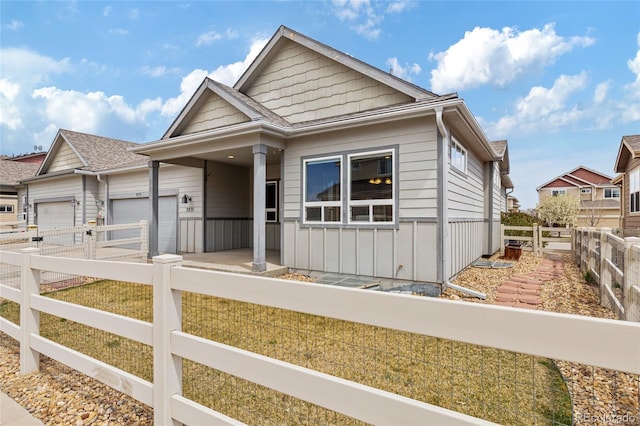view of front of house with board and batten siding, an attached garage, and a fenced backyard