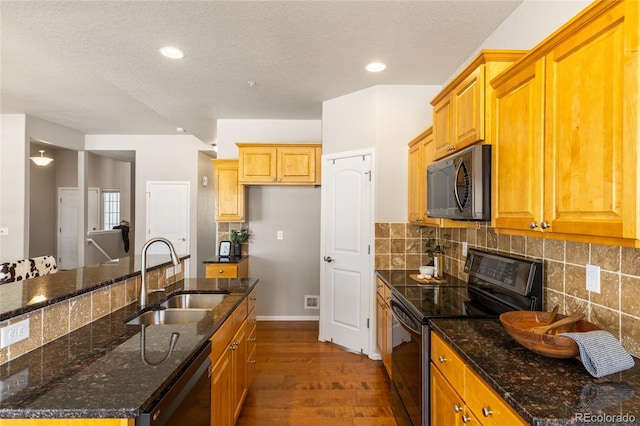 kitchen with black appliances, decorative backsplash, a sink, and dark wood-style floors