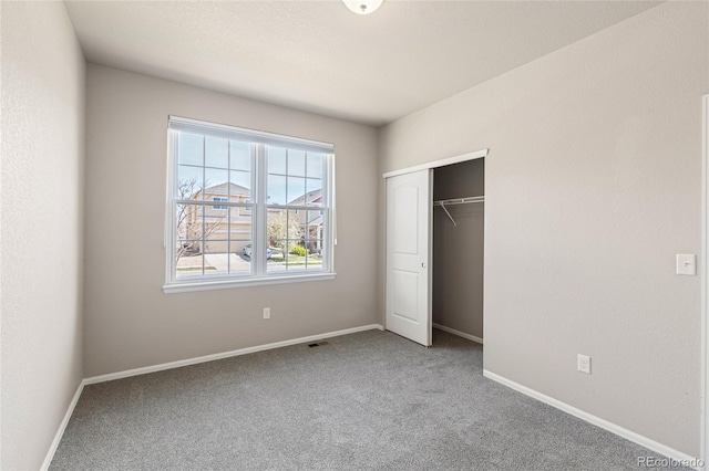 unfurnished bedroom featuring baseboards, carpet flooring, and a closet