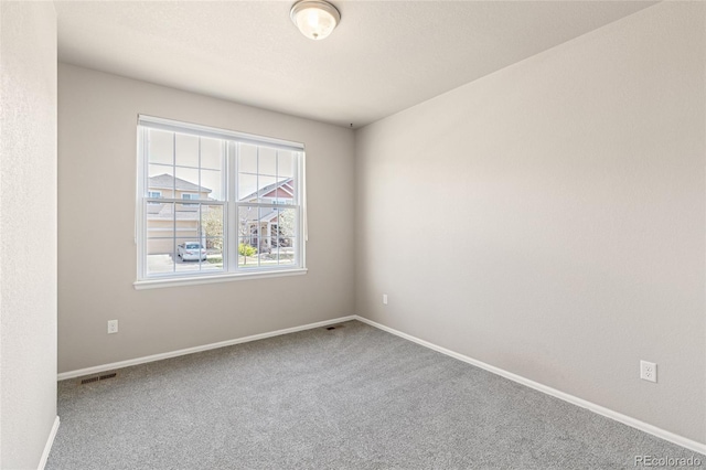 unfurnished room featuring baseboards, visible vents, and carpet flooring