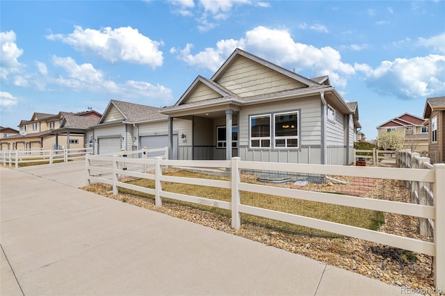 bungalow-style house featuring a garage, a fenced front yard, a residential view, and concrete driveway