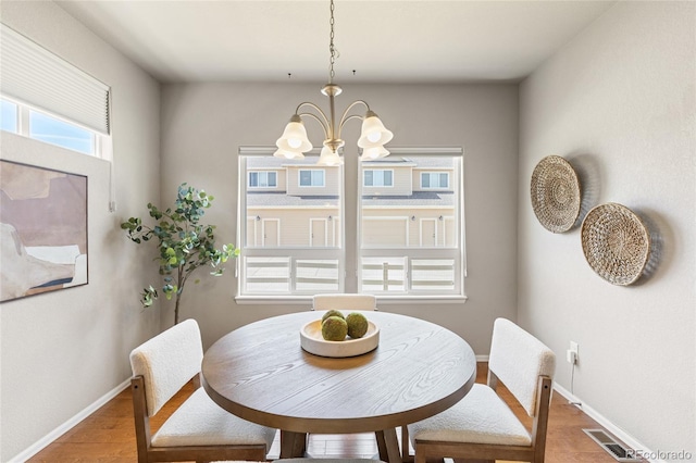 dining room featuring light wood finished floors, baseboards, visible vents, and a chandelier
