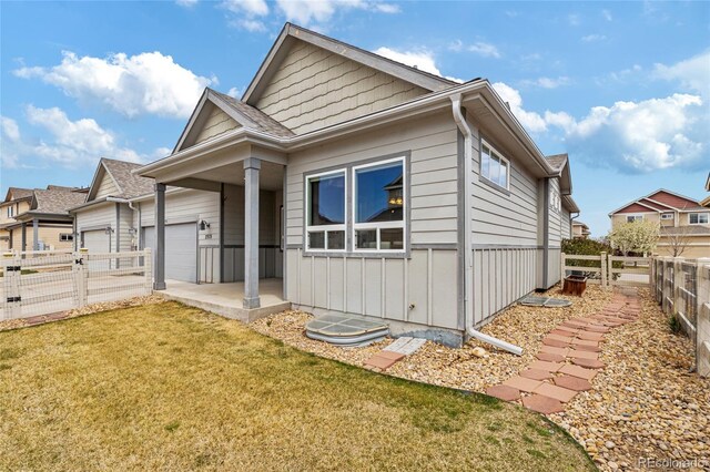 view of front facade with a front lawn, board and batten siding, a fenced backyard, and a garage