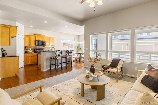 living room featuring light wood-type flooring, visible vents, recessed lighting, light colored carpet, and ceiling fan with notable chandelier