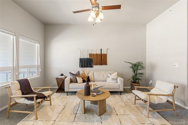 living area featuring light colored carpet, ceiling fan, and baseboards