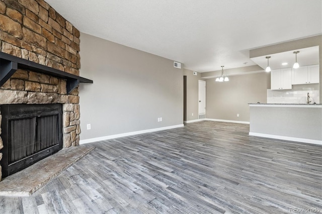 1777 S Pitkin St Unit A, Aurora, CO 80017 - unfurnished living room with wood finished floors, a fireplace, and a chandelier