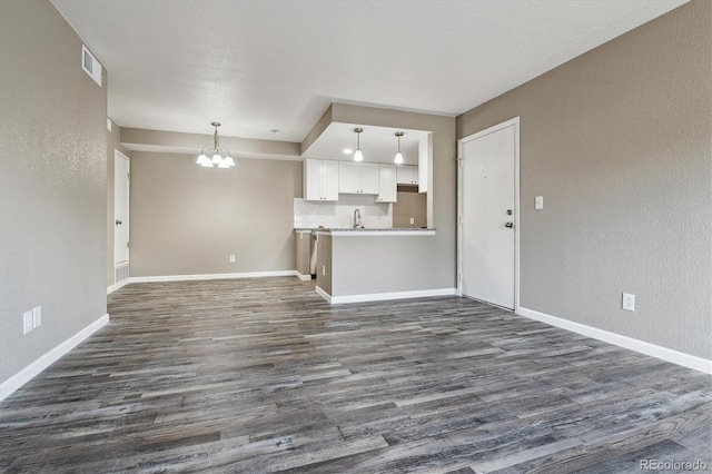 1777 S Pitkin St Unit A, Aurora, CO 80017 - unfurnished living room featuring a chandelier, dark wood-style floors, and a textured wall