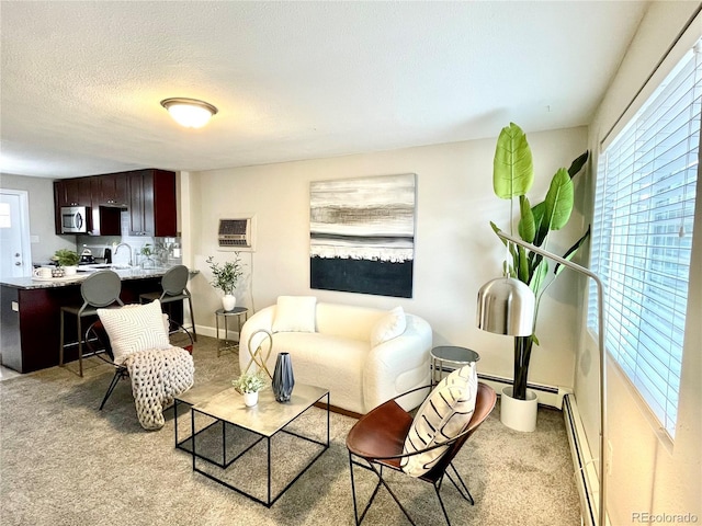 living area featuring plenty of natural light, a baseboard heating unit, a textured ceiling, and light colored carpet