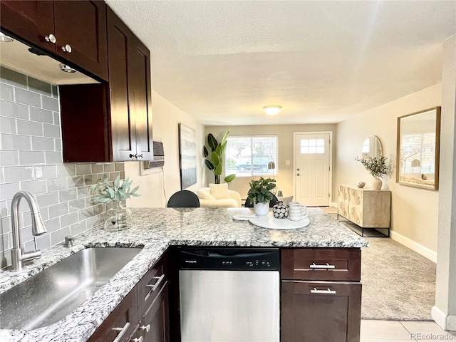 kitchen featuring dark brown cabinetry, light colored carpet, backsplash, stainless steel dishwasher, and a sink