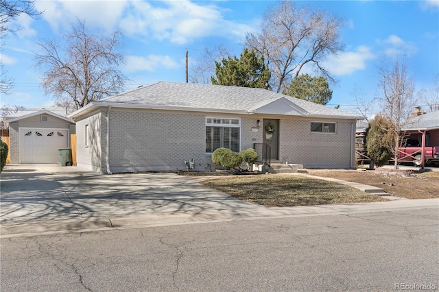 single story home featuring a garage, brick siding, an outdoor structure, driveway, and roof with shingles