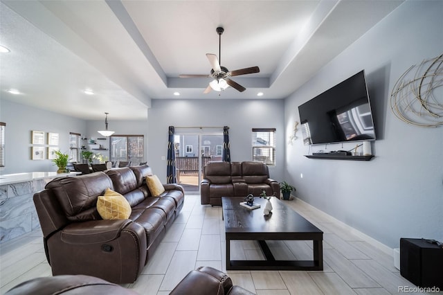 living room with ceiling fan and a tray ceiling