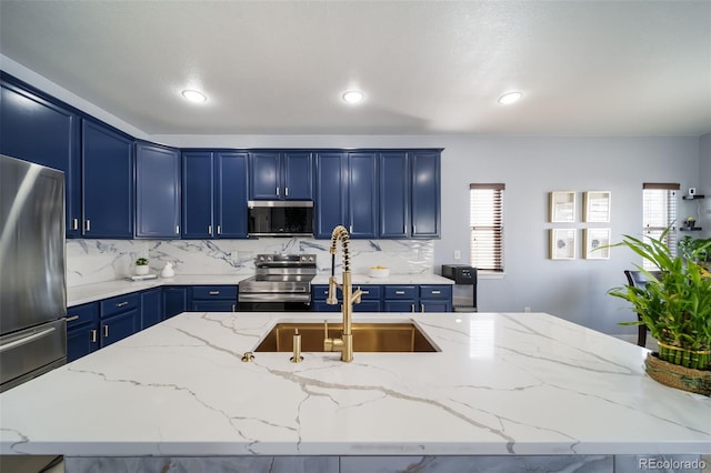 kitchen with blue cabinetry, appliances with stainless steel finishes, and light stone countertops