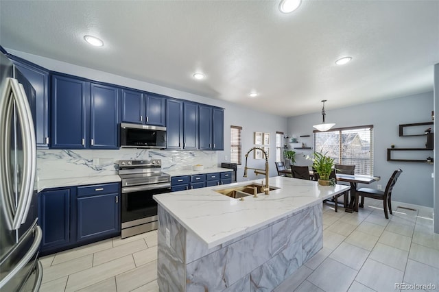 kitchen with pendant lighting, sink, appliances with stainless steel finishes, blue cabinets, and a center island with sink