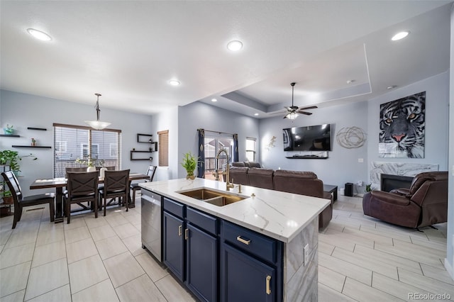 kitchen featuring sink, a center island with sink, a tray ceiling, blue cabinets, and stainless steel dishwasher