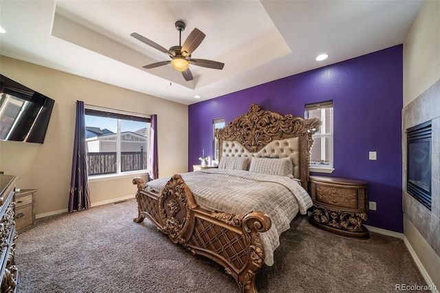 bedroom with ceiling fan, a tray ceiling, carpet floors, and multiple windows