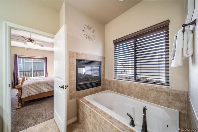 bathroom featuring tile patterned flooring, a fireplace, tiled bath, and ceiling fan