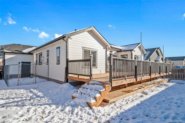 snow covered rear of property with a deck