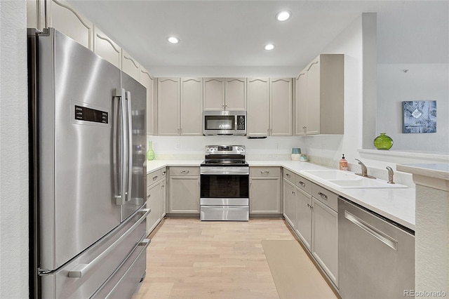 kitchen with gray cabinetry, sink, stainless steel appliances, and light wood-type flooring