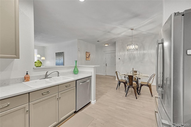 kitchen featuring appliances with stainless steel finishes, light wood-type flooring, sink, pendant lighting, and gray cabinets