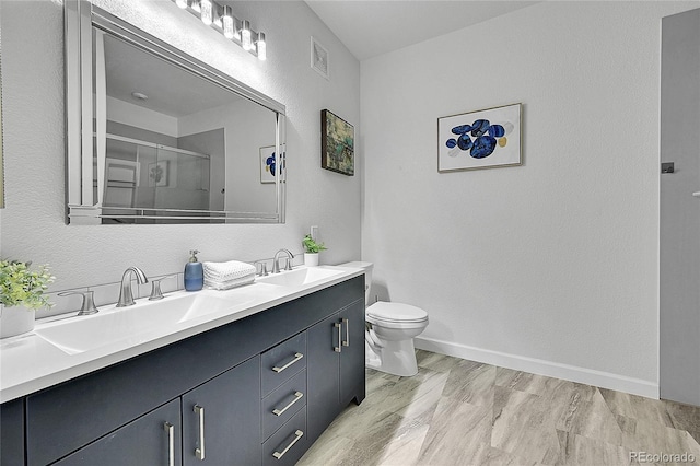 bathroom featuring a shower with door, vanity, and toilet