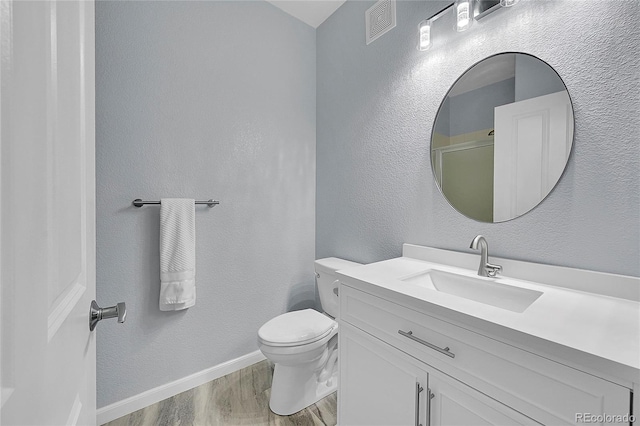 bathroom featuring vanity, hardwood / wood-style flooring, toilet, and a shower with shower door