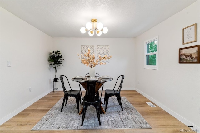 1815 Ingalls St, Lakewood, CO 80214 - dining room featuring a chandelier, light wood-style flooring, baseboards, and a textured ceiling